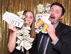 A silly couple with the money boa and beer props