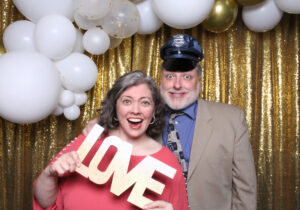 Using the photo booth props to take the selfie to the next level with a balloon arch and gold sequin backdrop.