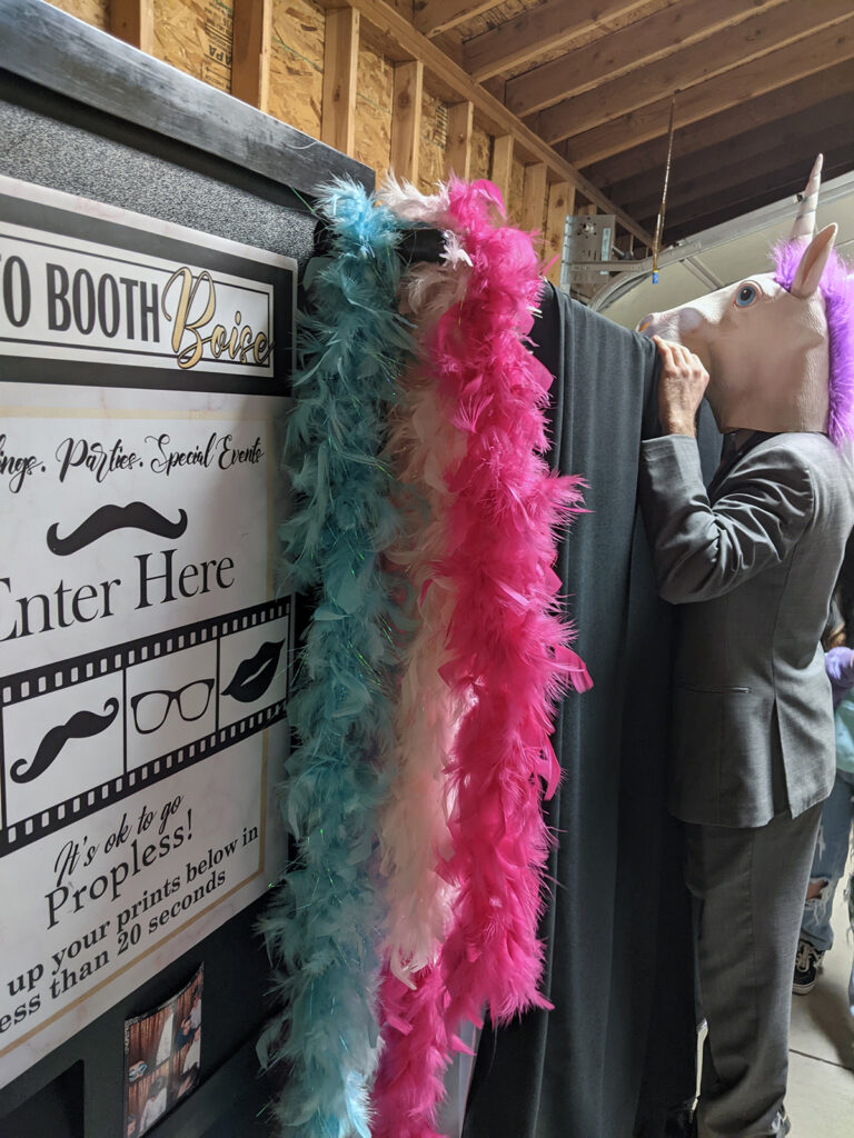 A man dressed as a unicorn looking over the top of the photo booth.
