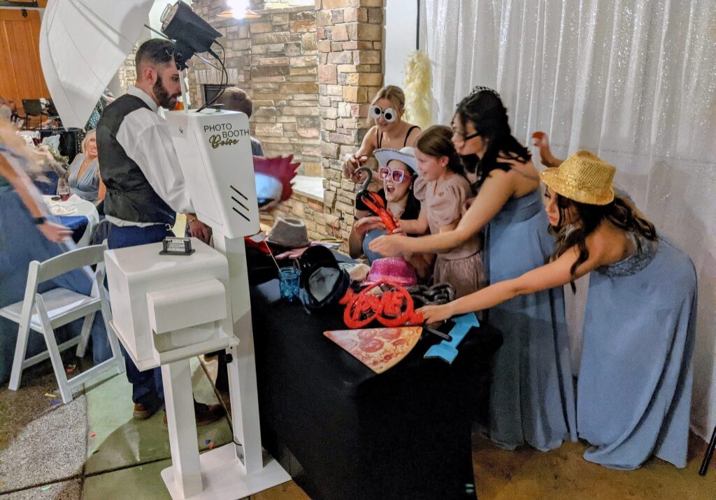 Bridesmaids and children reaching for photo booth props in between photos